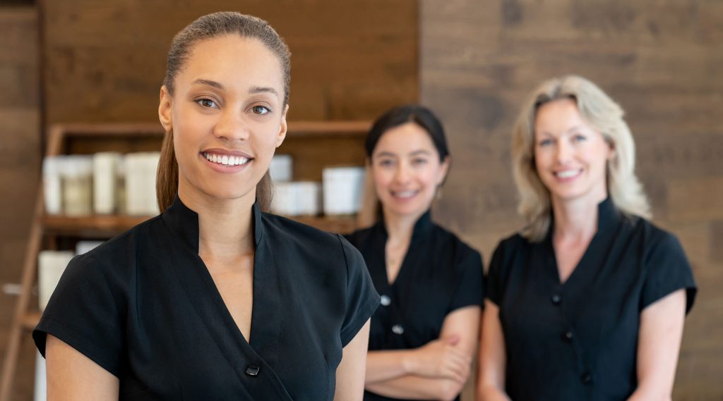 Portrait of a group of women working at a spa and looking at the camera smiling - beauty concepts
