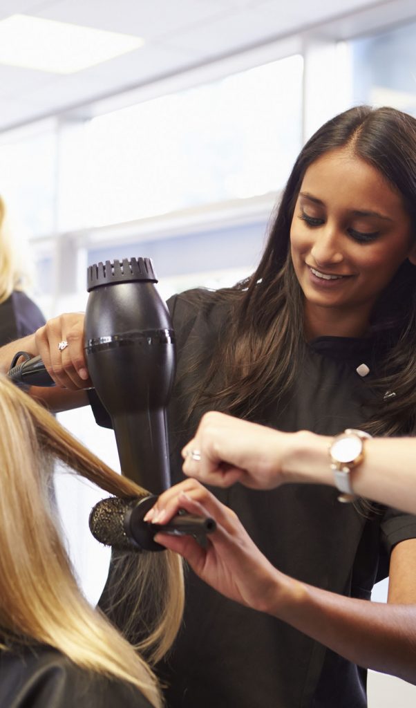Teacher Helping Students Training To Become Hairdressers